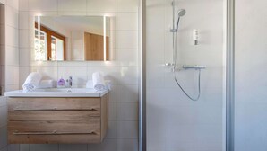 Une salle de bain moderne avec un meuble-lavabo en bois, un grand miroir et une douche à parois de verre.