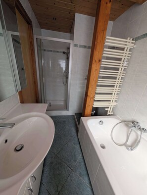 Een badkamer met een douche, twee wastafels en een bad.