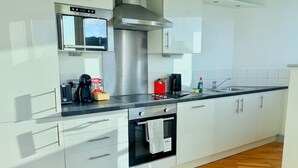 A modern kitchen with white cabinets, a stainless steel range hood, a built-in oven, a microwave, and a coffee maker. - Bright 2-bed Apartment York City Centre - Walk to Everything (York)