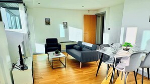 A modern living room with a sofa, a coffee table, and a dining area with a table set for four. - Bright 2-bed Apartment York City Centre - Walk to Everything (York)
