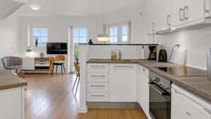 A modern kitchen with white cabinets, a built-in oven, and a dining area with a TV and seating. - "Babo" - 250m from the sea by Interhome (Bogense)