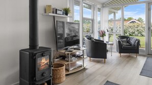 Una sala de estar moderna con una chimenea de leña, un televisor de pantalla plana y asientos cómodos.