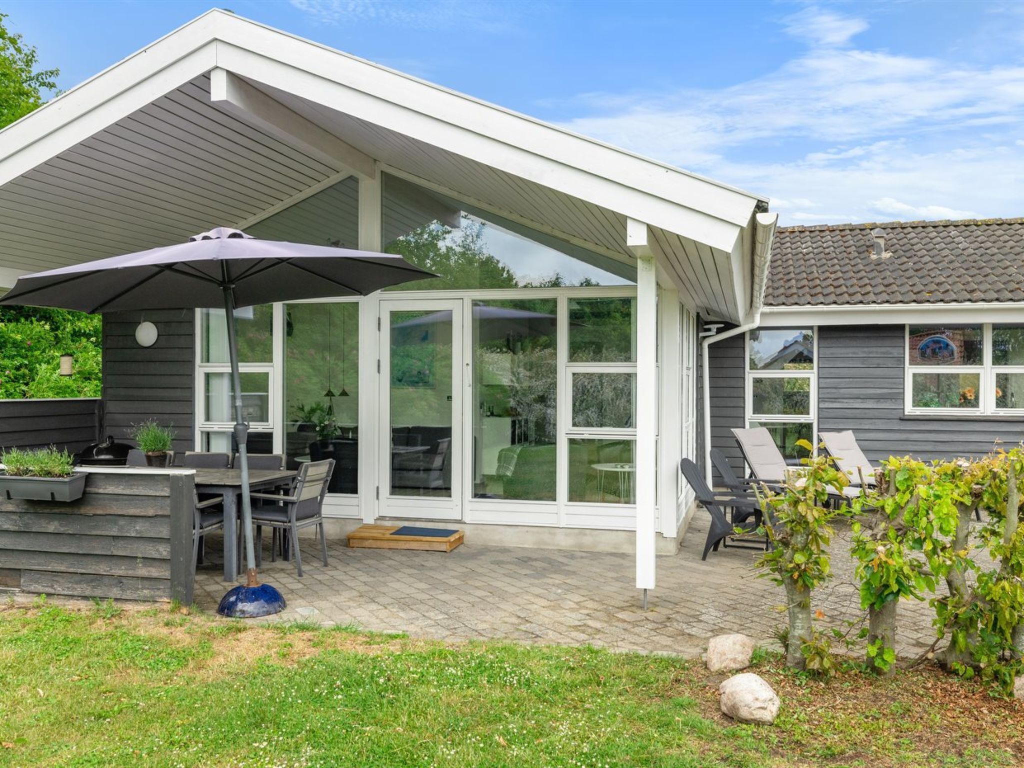 A covered patio area with a table and chairs, a grill, and a large umbrella.