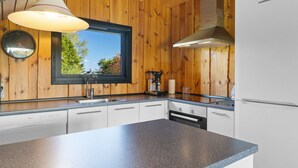 A kitchen with wooden walls, a window, a sink, a stove, and a refrigerator. - "Allin" - 350m from the sea by Interhome (Otterup)