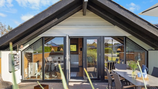 A modern house with a glass-enclosed patio, outdoor seating, and a visible garden. - "Allin" - 350m from the sea by Interhome (Otterup)