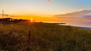 A coastal landscape with a sunset, grassy fields, and a distant shoreline. - "Nedelko" - 20m from the sea by Interhome (Otterup)