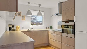 A modern kitchen with wooden cabinets, a built-in oven, and pendant lighting. - "Solvejg" - 280m from the sea by Interhome (Otterup)
