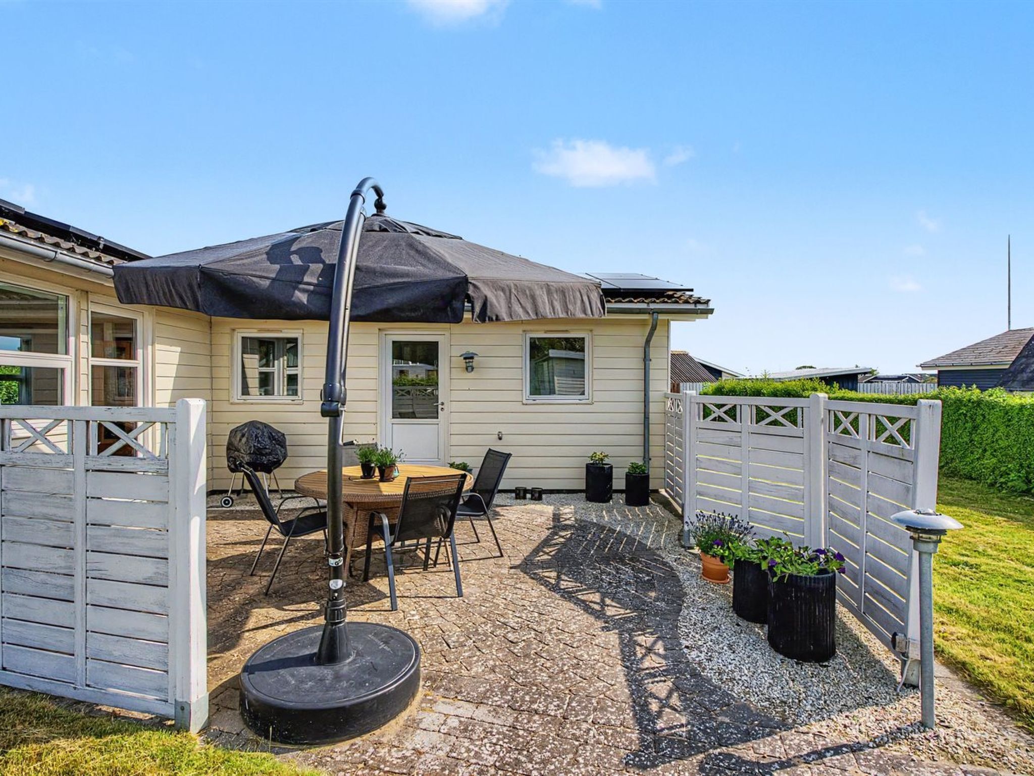 Een terras met een tafel en stoelen, een barbecue, en een overdekt gedeelte met een tafel en stoelen.