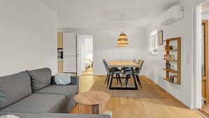A modern living room with a grey sofa, a wooden coffee table, and a dining area with a table and chairs. There is a kitchen visible in the background. - "Solvejg" - 280m from the sea by Interhome (Otterup)