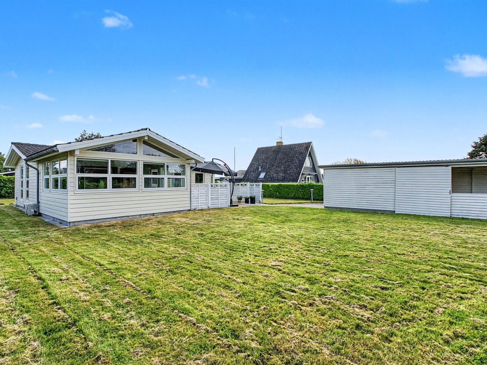 A residential area with a house featuring a large garage, a well-maintained lawn, and a neighboring house with a sloped roof.