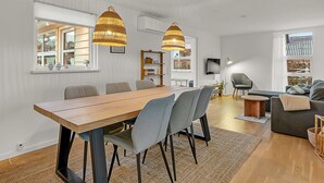 A modern living room with a wooden dining table, grey chairs, and two hanging wicker lamps. - "Solvejg" - 280m from the sea by Interhome (Otterup)