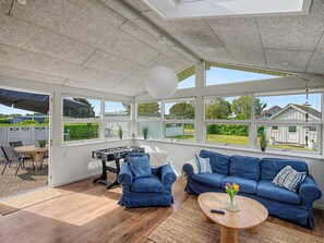 Ein Wintergarten mit einem Kicker, zwei blauen Sofas und einem Holztisch.