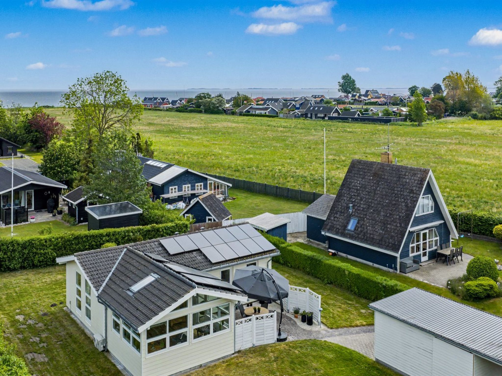A residential area with houses, a grassy field, and a body of water in the background.