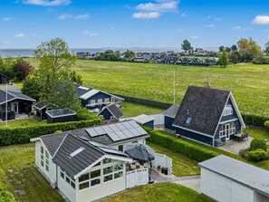Un barrio residencial con casas, un campo cubierto de césped y vistas al mar.