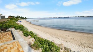 Ein Strand mit freiem Blick auf das Wasser, einem sandigen Ufer und einer entfernten Skyline.