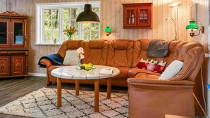 Una sala de estar acogedora con un sofá de cuero marrón, una mesa redonda de centro y un mueble de madera.