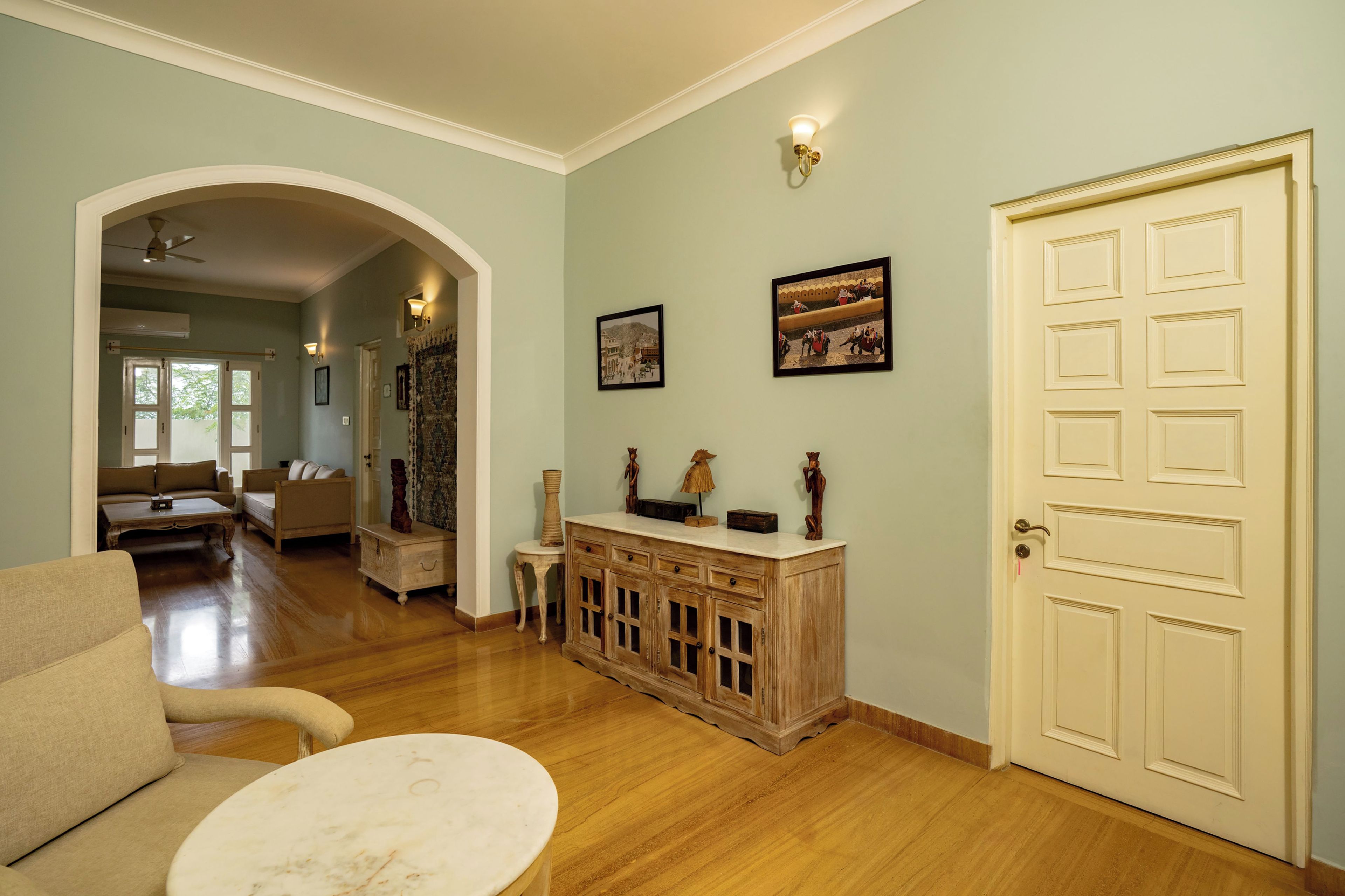 Amplia sala de estar con piso de madera, un sofá, una mesa de centro y una puerta con un panel decorativo.