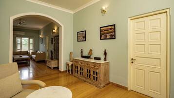 Amplia sala de estar con piso de madera, un sofá, una mesa de centro y una puerta con un panel decorativo.