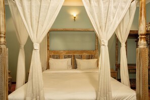 A four-poster bed with a canopy, a wooden headboard, and a wall-mounted light fixture. - Ramat Niwas by Kutani Stays (Jaipur)