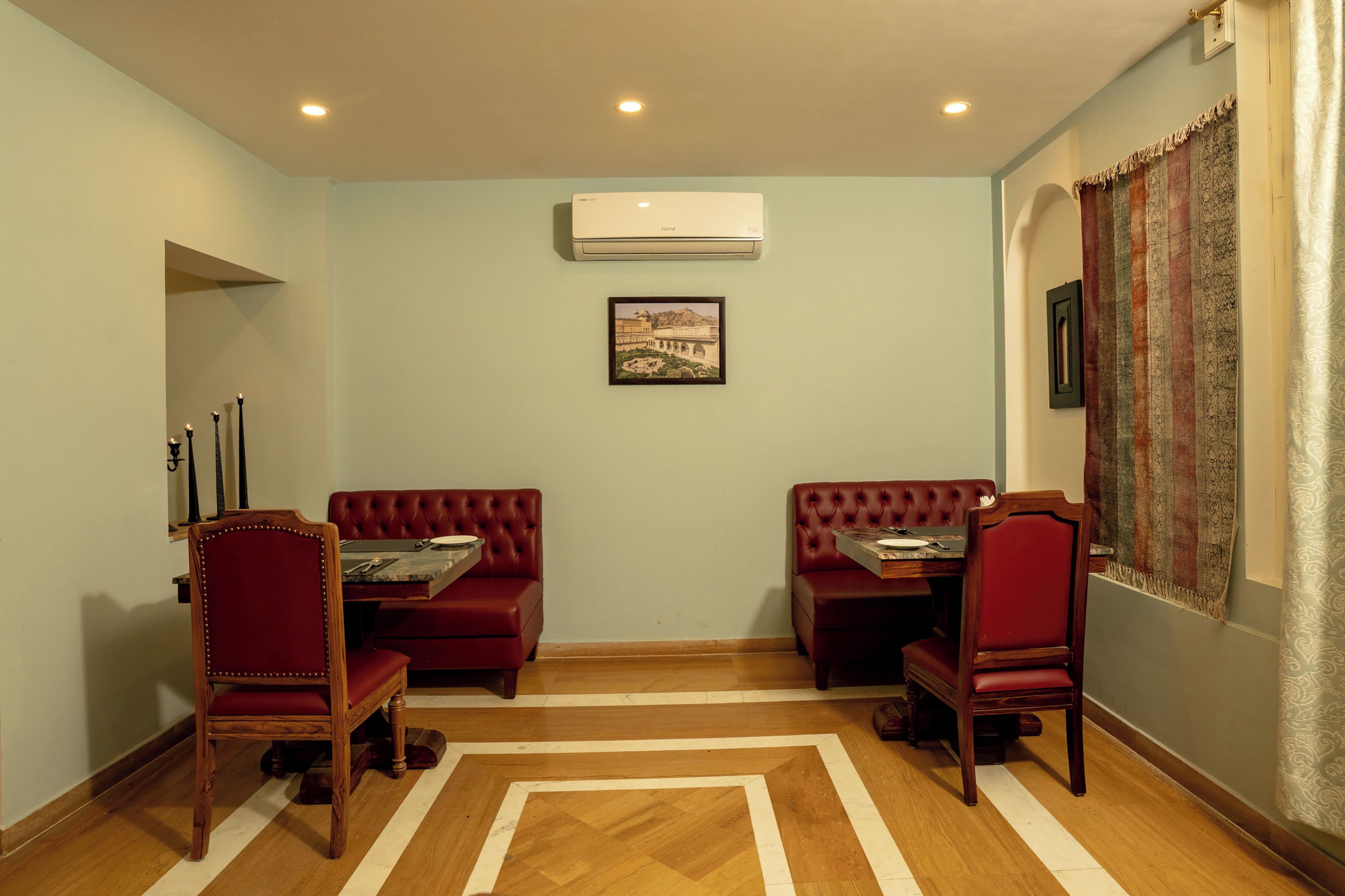 Una habitación con dos sofás de cuero rojo, una mesa de madera y una cortina estampada.