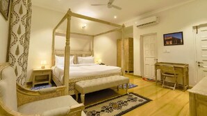 A four-poster bed with a canopy, a wooden desk, a chair, and a small bedside table with a lamp. - Ramat Niwas by Kutani Stays (Jaipur)