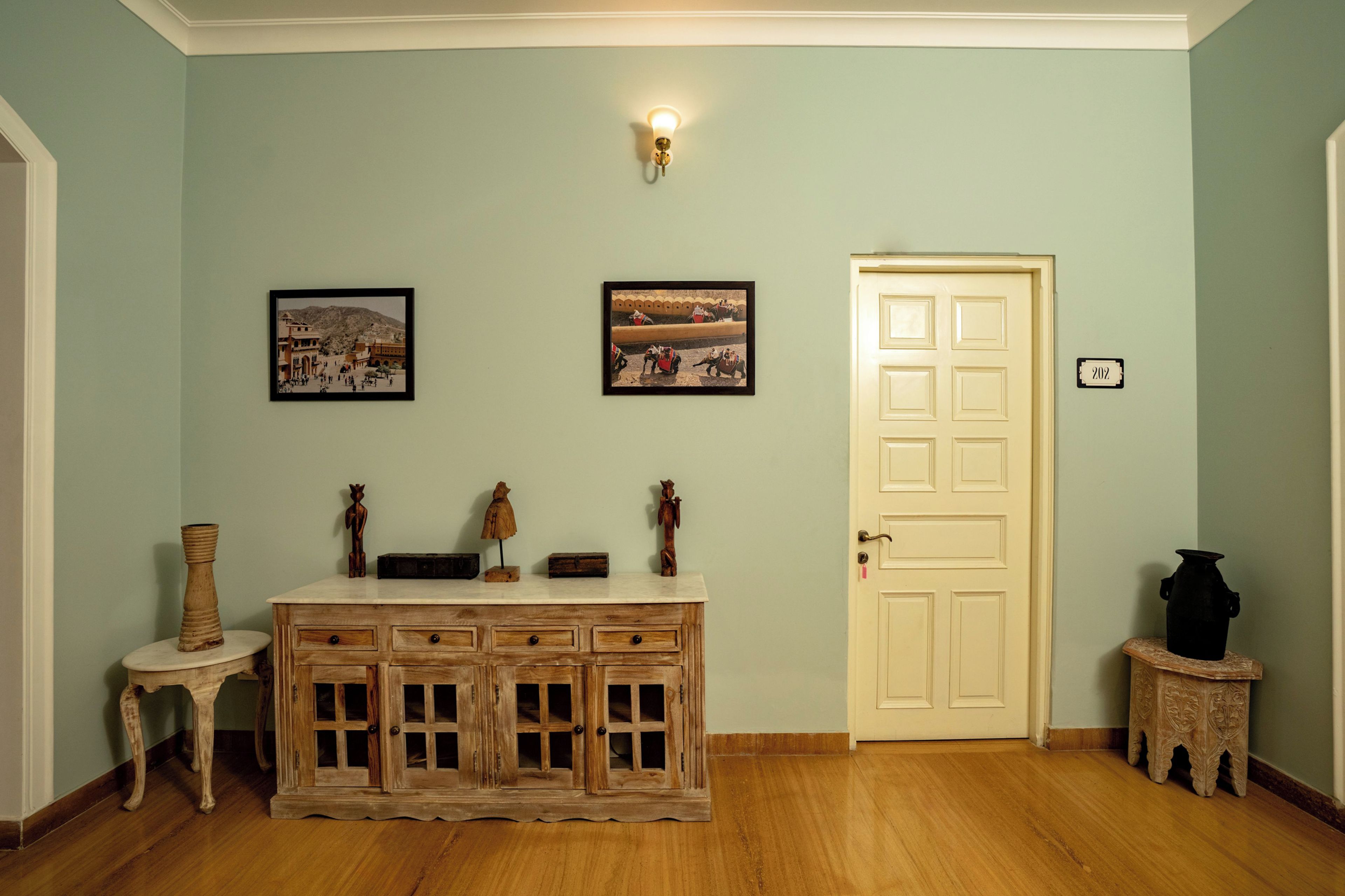 Una habitación con un armario de madera, una puerta con placa de número y dos cuadros en la pared.