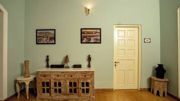 Una habitación con un armario de madera, una puerta con placa de número y dos cuadros en la pared.