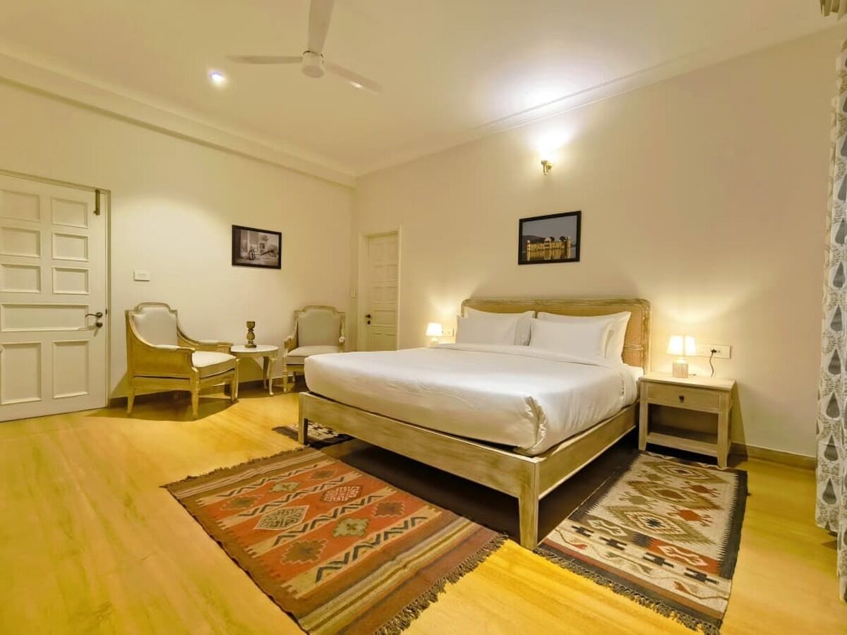 A bedroom with a bed, a chair, a nightstand, and a door.