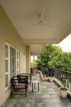 A balcony with a ceiling fan, a table, and two chairs. - Ramat Niwas by Kutani Stays (Jaipur)