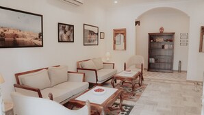 A living room with a sofa, chairs, a coffee table, a bookshelf, and framed pictures on the wall. - Ramat Niwas by Kutani Stays (Jaipur)
