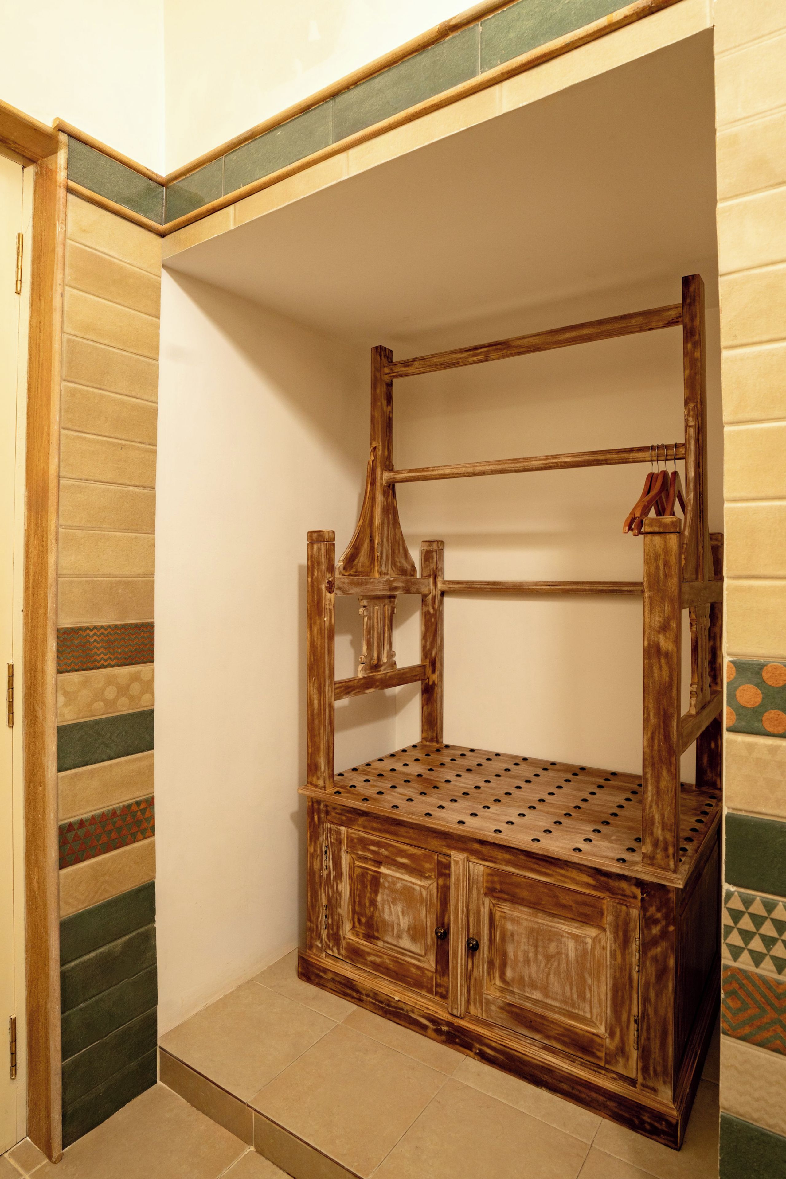 Habitación de esquina con cama de madera, una puerta y suelo de baldosas.