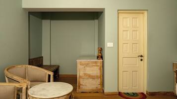 Una habitación con un banco de madera, una mesita y una puerta con felpudo.
