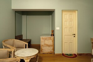 A room with a wooden bench, a small table, and a door with a doormat. - Ramat Niwas by Kutani Stays (Jaipur)