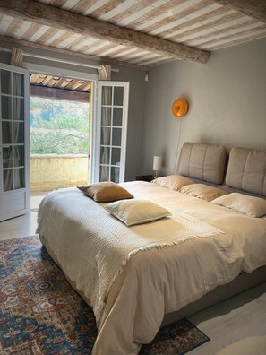 Un dormitorio con una cama grande, una mesita de noche, una lámpara y vistas a través de una puerta corrediza.