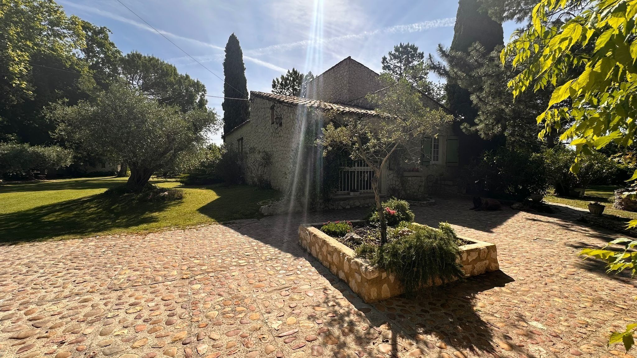 Un bâtiment en pierre, doté d’un toit en tuiles, entouré d’un jardin avec un chemin pavé.