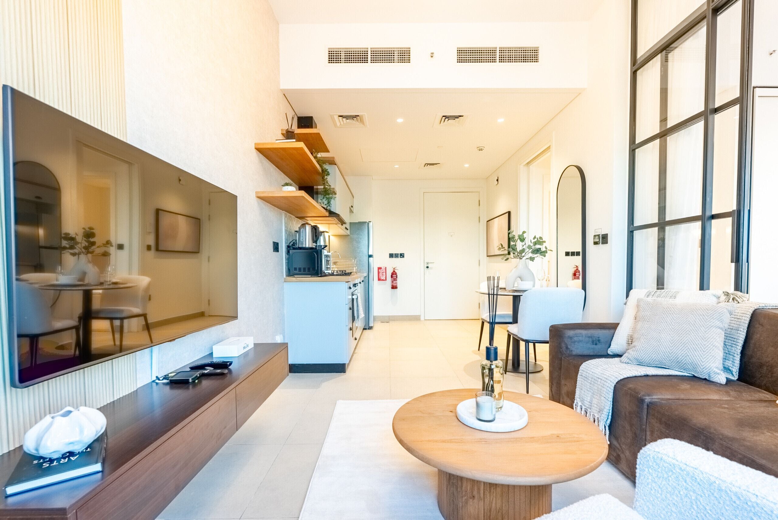 A modern hotel lobby with a seating area, a kitchen, and a large window.