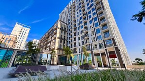 Un edifici modern de grans alçades amb múltiples balcons, grans finestres i un jardí a la teulada.
