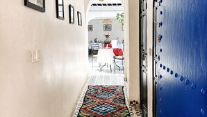A hallway with a patterned rug, a blue door with rivets, and a chandelier. - Riad lazord de Marrakech  (Marrakech)