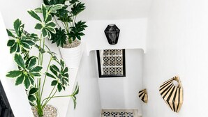 A staircase with geometric patterned tiles, white walls, and potted plants. - Riad lazord de Marrakech  (Marrakech)