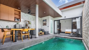 Una cocina moderna con armarios de madera, comedor y piscina.