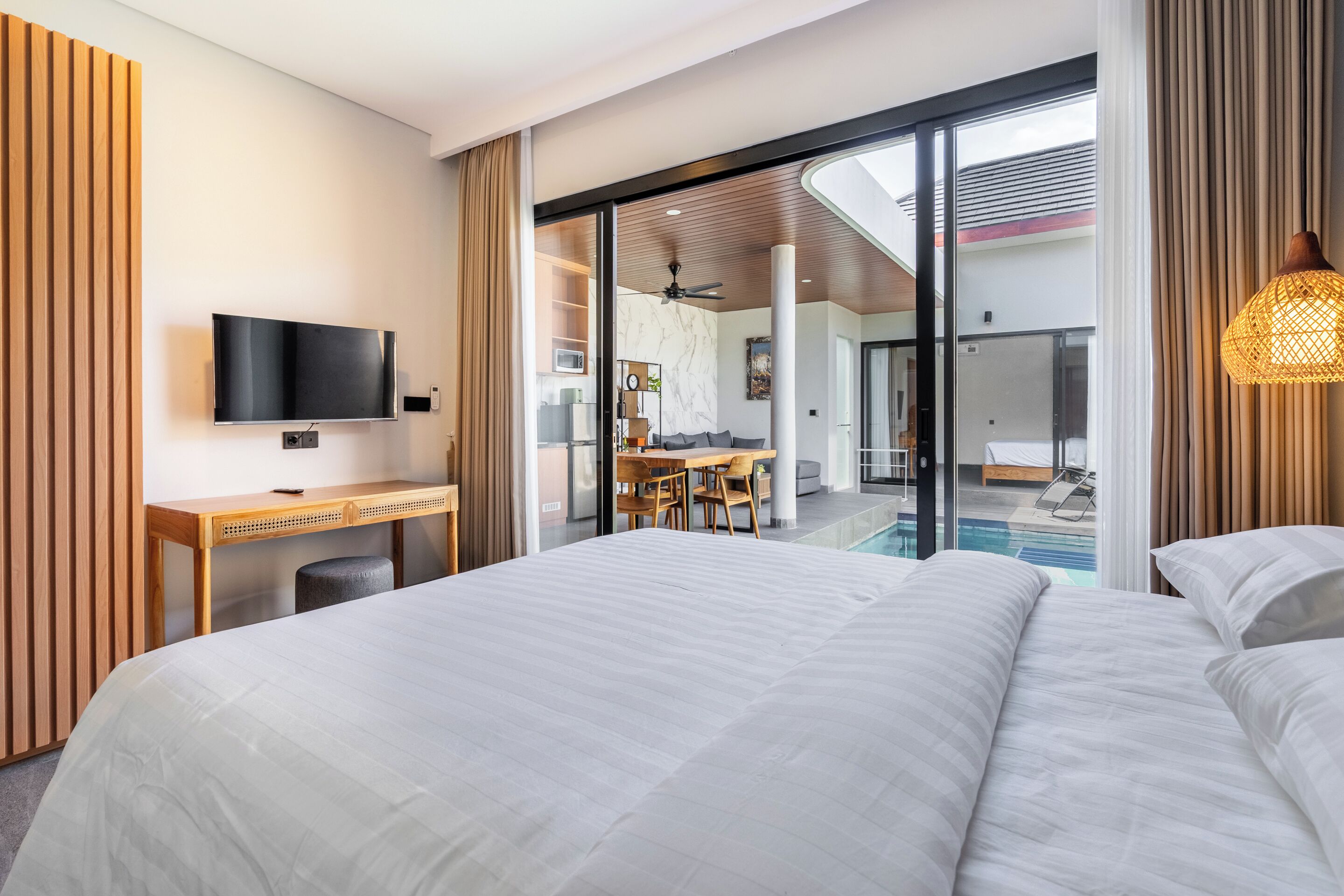 Une chambre d’hôtel moderne dotée d’un grand lit, d’un bureau, d’une télévision et offrant une vue sur une piscine.