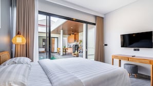 Una habitación de hotel moderna con una cama grande, un escritorio, un televisor y vistas a la cocina y la sala de estar.