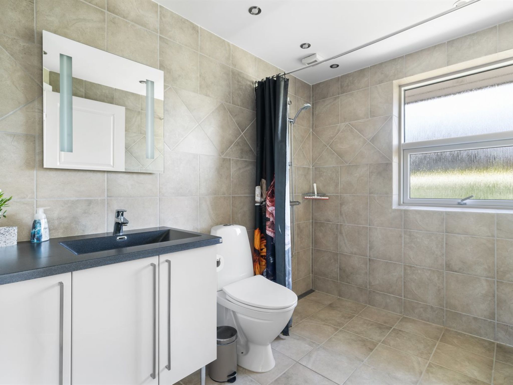 A modern bathroom with a shower, toilet, and sink.