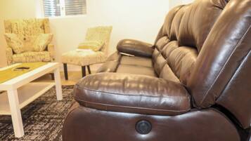 A brown leather sofa with a button, a patterned armchair, and a small table in a living room.
