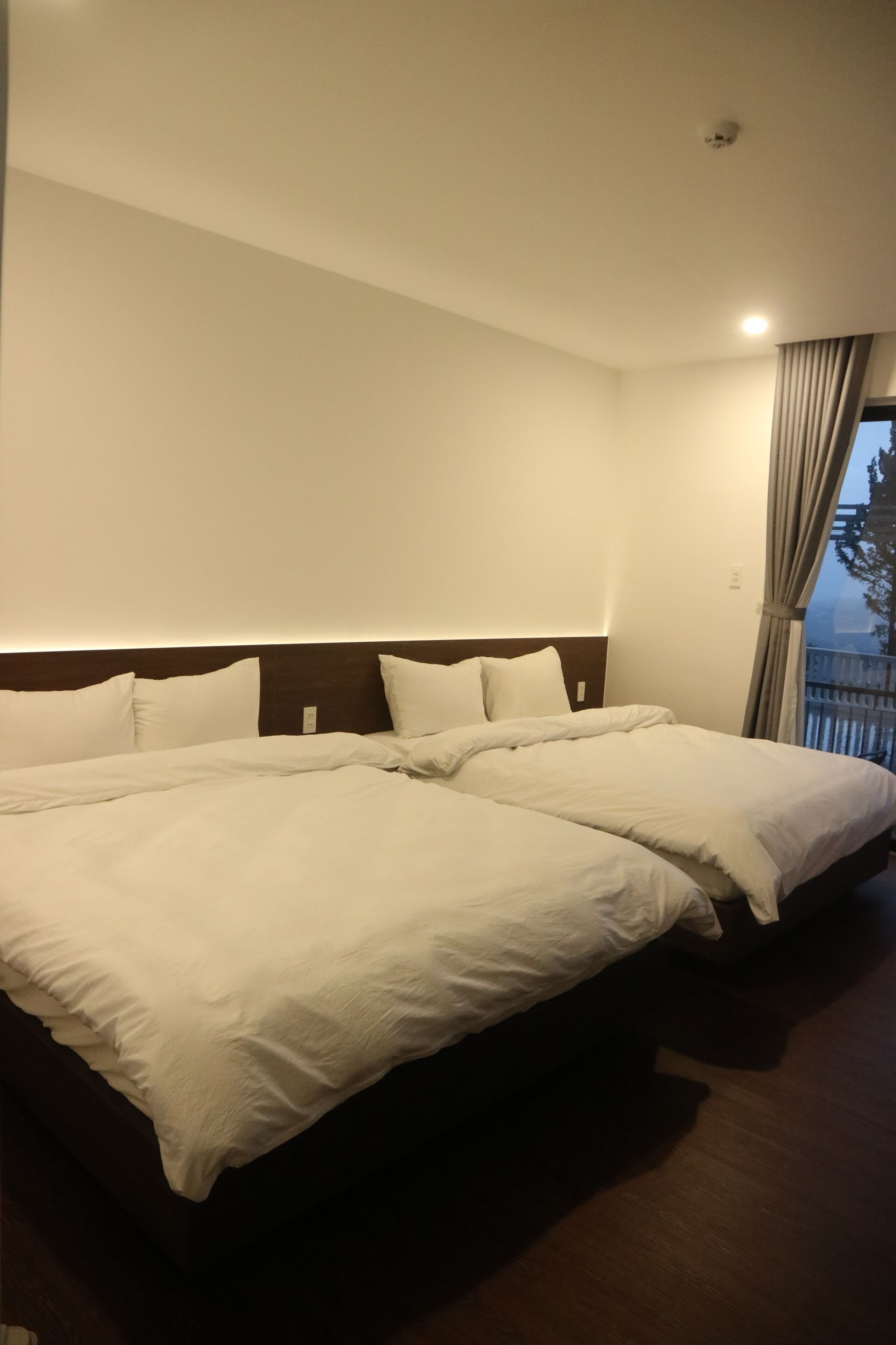 A hotel room with two beds, a wooden headboard, and a window with curtains.
