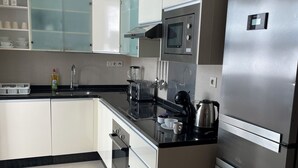 A modern kitchen with white cabinets, a stainless steel refrigerator, a microwave, and a toaster. - Beautiful apartment in downtown Agadir at Galerie Talborjt (Agadir)