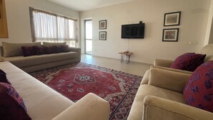 A living room with a sofa, armchairs, a TV, and a patterned rug. - Beautiful apartment in downtown Agadir at Galerie Talborjt (Agadir)