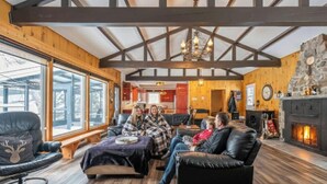 Un salon chaleureux avec des poutres en bois, une cheminée et de grandes fenêtres.