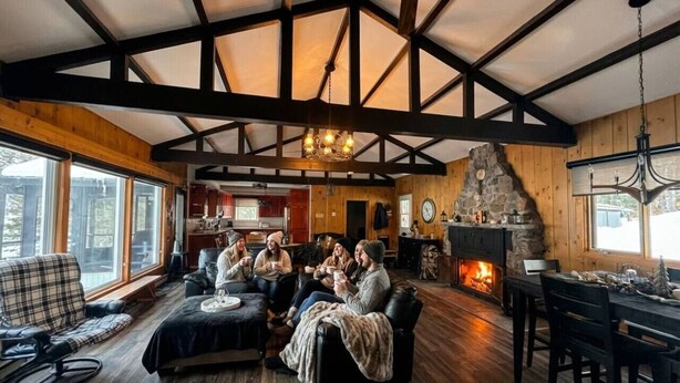 Un salon chaleureux avec une cheminée, des poutres en bois et un mur d’accent en pierre.
