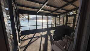 Un espace extérieur abrité, doté d’un banc et d’une table, et délimité par une clôture en treillis métallique.